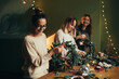 © polinaloves - Happy women making Christmas wreath using natural pine branches and festive decorations.