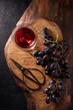 on a rough wooden board, a bunch of black grapes and a pair of scissors and a glass of red wine