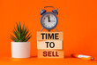 Time to sell symbol. alarm clock and time to sell, word concept on wooden blocks. Beautiful orange background, succulent on desk, business and sales concept. Copy space