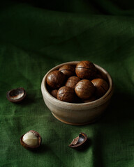 Wall Mural - macadamia nut in a ceramic bowl, dark green background, minimalism, no people, close-up