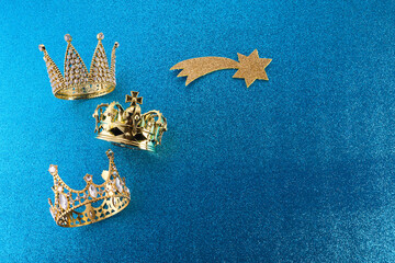 Wall Mural - Epiphany Day or Dia de Reyes Magos concept. Three gold crowns on blue sparkling background