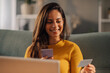 © Zamrznuti tonovi - Happy woman sitting at home making online purchase on phone.
