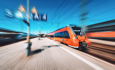 Wall Mural - red high speed train in motion on the railway station at sunset. fast modern intercity train and blu