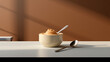 A tub of gourmet salted caramel ice cream, with a creamy and smooth texture. The tub is presented on a minimalist table with neutral colors and a modern spoon next to it. In the background a smooth br