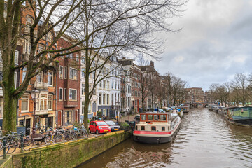 Cityscape on a sunny winter day - view of the water canal with houseboats in the historic center of Amsterdam, the Netherlands, 2 January, 2018