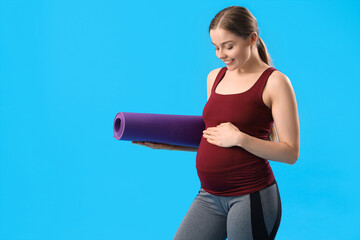 Poster - Pregnant young woman with yoga mat on blue background