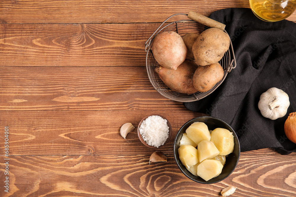 Boiled and raw potatoes on wooden background