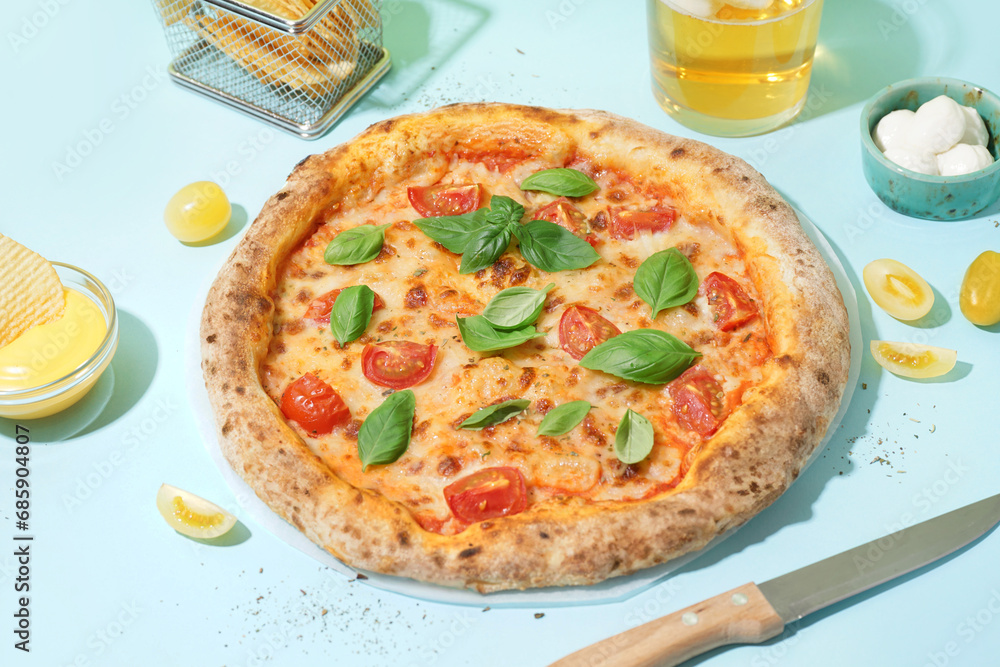 Tasty pizza Margarita with tomatoes and basil on blue table