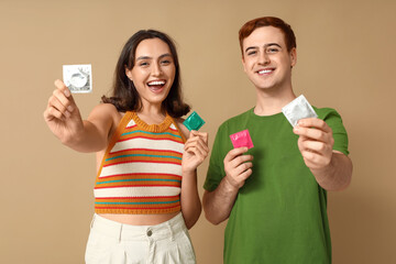 Young couple with condoms on beige background. Safe sex concept