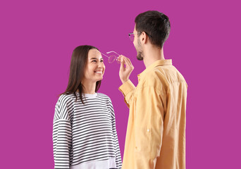 Wall Mural - Young couple with eyeglasses on purple background