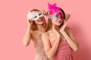 Wall Mural - Beautiful young women in carnival masks on pink background