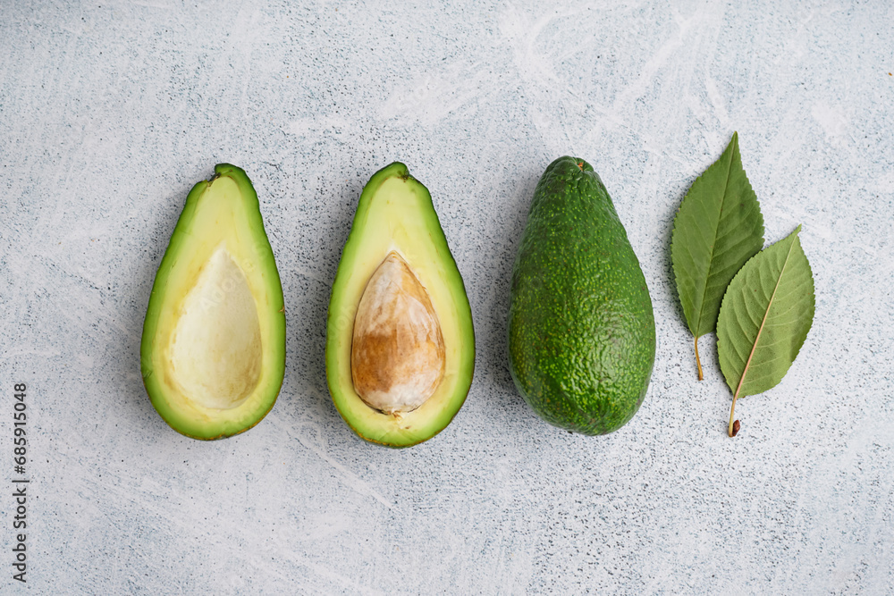 Fresh ripe avocados and leaves on white background