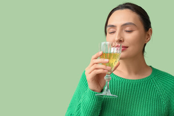 Poster - Beautiful young woman with glass of white wine on green background