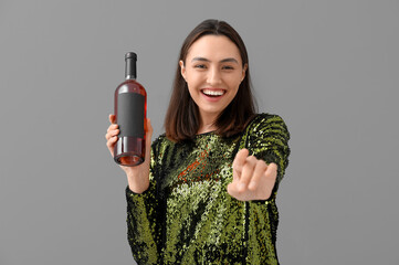 Sticker - Beautiful young woman with bottle of wine on grey background