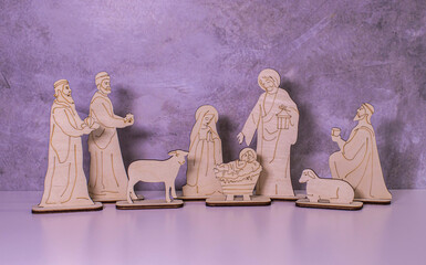 A wooden Christmas Nativity set with the holy family gazing at baby Jesus with a bokeh background