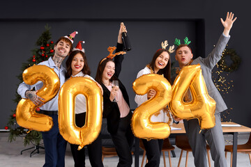 Canvas Print - Young colleagues with figure 2024 and champagne celebrating New Year at corporate party in office