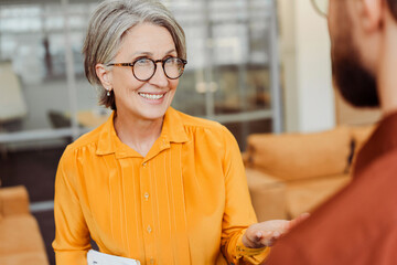 portrait of smiling confident senior woman wearing eyeglasses communication with colleague