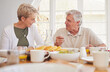 © K Davis/peopleimages.com - Breakfast, talking and lunch with senior couple, eating and happy together in a home. Love, support and care on a dining room with a smile and food with bonding in the morning with fruit in house