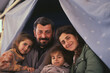 © Adin - Portrait of refugee family dad with mom and childs at border checkpoint of tent camp. Concept Illegal immigrant due to war, loss of home