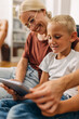 © cherryandbees - Closeup view of a happy moment with a young boy and his mom playing a game using tablet.