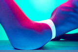 Cropped image of female body, slim belly against blue background in neon light. Model posing in underwear. Body aesthetics, beauty
