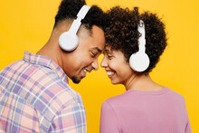 Young Couple Two Friends Family Man Woman Of African American Ethnicity Wear Casual Clothes Together Listen Music In Headphones Look To Each Other Touch Forehead Isolated On Plain Yellow Background.