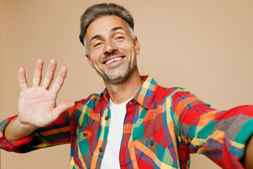 Close up adult man he wear red shirt white t-shirt casual clothes doing selfie shot pov on mobile cell phone waving hand isolated on plain pastel light beige color background studio Lifestyle concept