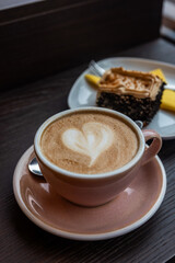 Wall Mural - cup of coffee and cake on table in cafe,A cup of coffee with latte art.latte macchiato in a pink cup