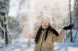 © sushytska - Portrait of a beautiful girl in winter clothes standing in a winter park on a sunny day and smiling. The winter vacation. Copy space.
