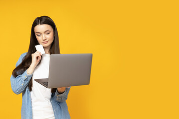 Wall Mural - Cute young woman with laptop and credit card in hands
