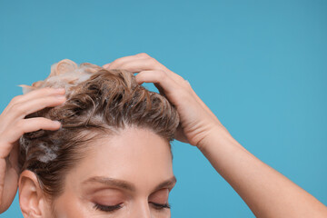 Wall Mural - Woman washing hair on light blue background, closeup. Space for text