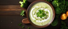 Wooden table with top view of cream soup made with broccoli and green peas.