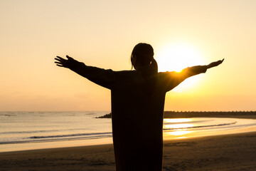 Canvas Print - Silhouette of woman stand at sunset in the beach with open arm