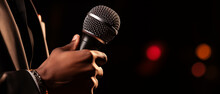 Microphone And Male Singer Close Up. Man Singing Into A Microphone, Holding Mic With Hands. Close Up Of Karaoke Microphone. Stage Spotlight. 