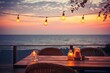 Outdoor restaurant at the beach. Tables at beach restaurant. Led light candles and wooden tables, chairs under beautiful sunset sky, sea view. Luxury hotel or resort restaurant 
