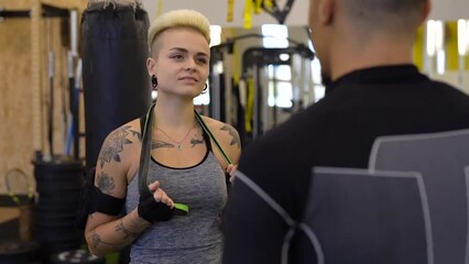 Wall Mural - Athletic woman talking witn her friend standing back during the training in gym