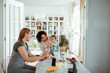© Marko Geber - Young lesbian couple feeding their child together at home