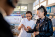 © Marko Geber - Young woman reading ingredients of product with pharmacist at drugstore