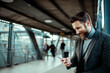 © Geber86 - Young bearded businessman checking smartphone at train station