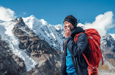 Wall Mural - portrait of sherpa man with backpack using walkie-talkie for calling rescue helicopter with mera pea