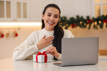 Poster - Celebrating Christmas online with exchanged by mail presents. Smiling woman thanking for gift during video call at home