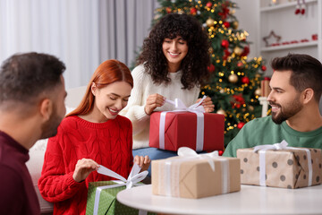 Canvas Print - Christmas celebration in circle of friends. Happy women opening gifts at home