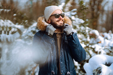 Wall Mural - A young bearded man walks in a snowy park. Happy man enjoying the weather on a winter sunny day. Concept of walks, weekends.