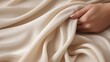 woman hand touching beige silky cashmere fabric closeup.
