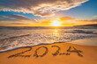 Sea sunrise of first new day for 2024 year text on beach sand