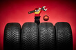 Winter car tires, big wheels service and hand of mechanic man with wrench and christmas ball on red background.