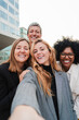 © Jose Calsina - Vertical portrait. Group of real successful business woman smiling and having fun taking a selfie together. Teamwork of entrepreneur females looking at camera. Happy startup ladies laughing at work
