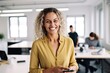 © Malynka - Business woman smiling at the camera and holding a cellphone, business entrepreneur at work. Happy worker using smartphone technology working on cellphone in office