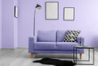 Interior of living room with lilac sofa, table and floor lamp near wall