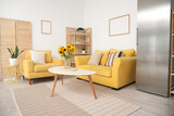Fototapeta Panele - Vase with beautiful sunflowers, yellow sofa and armchair in interior of stylish living room